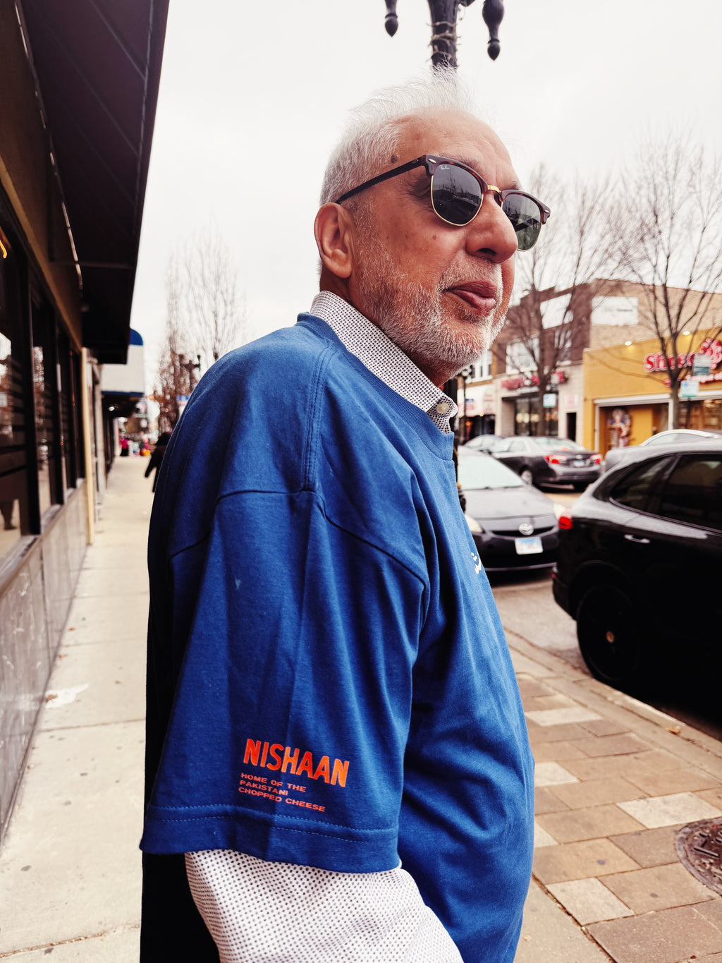 Man wearing a blue Nishaan shirt on a city street.